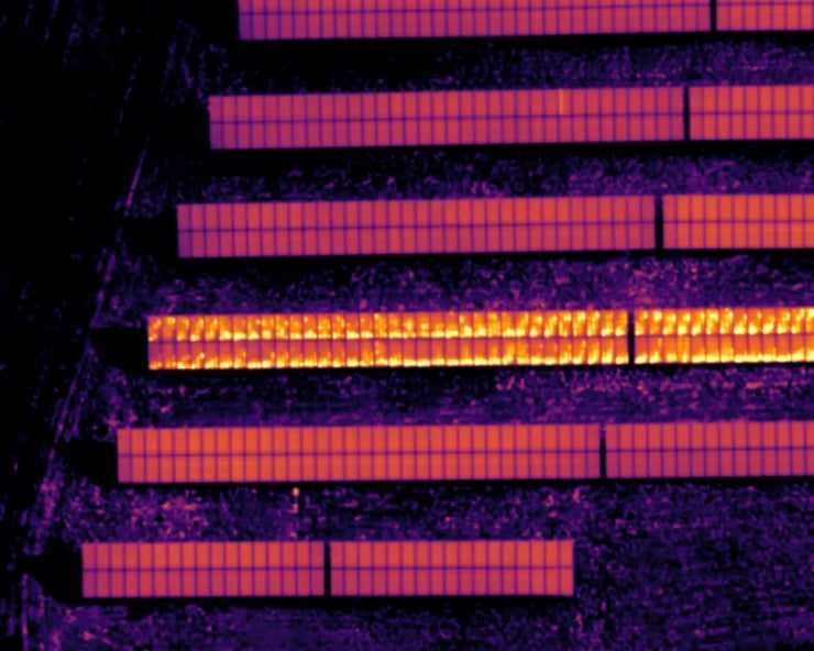 Aerial Infrared image (yellow hot) of a section of a site presenting with two strings with modules in short-circuit.